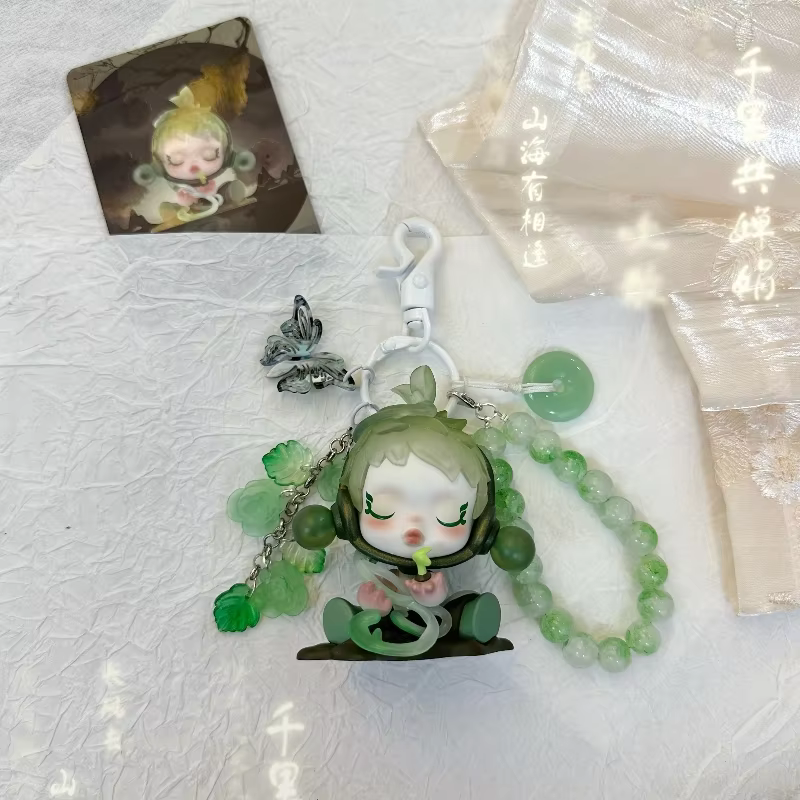 Clothed in flowing silks, patterned with motifs celebrating lunar beauty, and bearing a serene, half-smile, each glossy pendant reveals a miniature Skullpanda poised in royal court robes